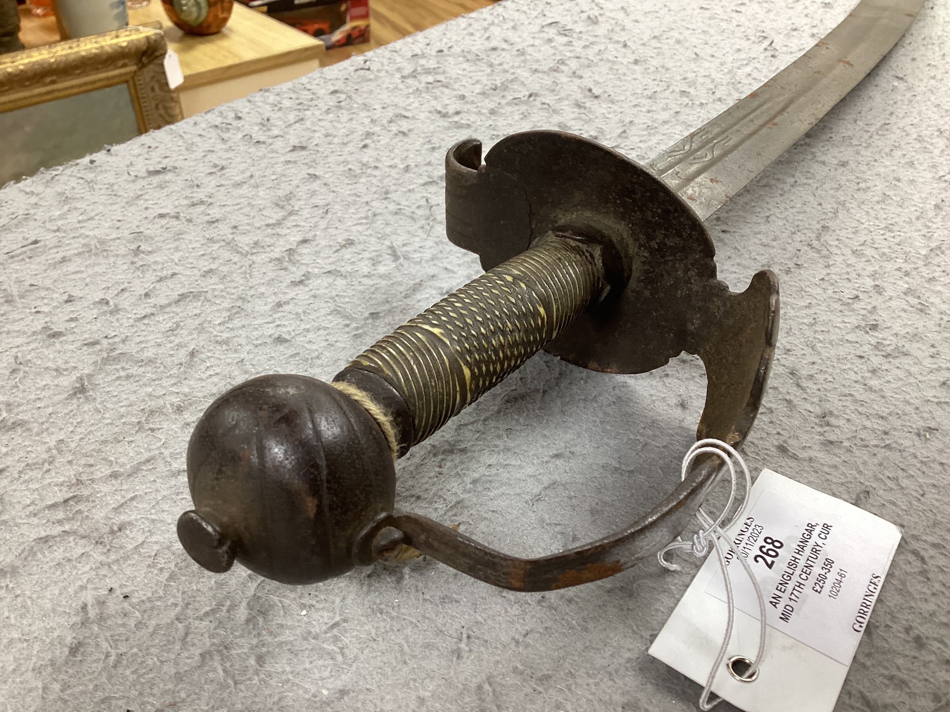 An English hangar, mid 17th century, curved fullered blade engraved with spurious date 1535 and running wolf mark, iron guard slightly reduced and swollen pommel, spirally carved and chequered bone grip, blade 67.5cm